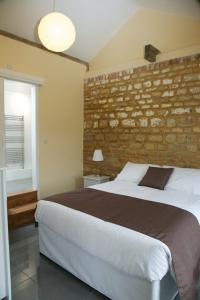 a bedroom with a large bed and a brick wall at Pheasants Roost at Tove Valley Cottages in Towcester