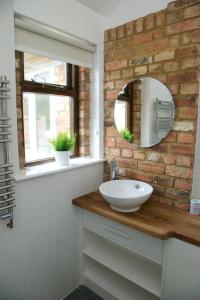 a bathroom with a white sink and a brick wall at Pheasants Roost at Tove Valley Cottages in Towcester