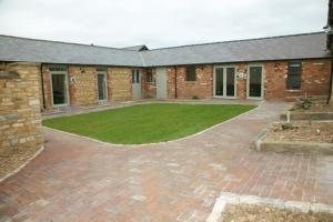 a brick building with a courtyard with a lawn at Pheasants Roost at Tove Valley Cottages in Towcester