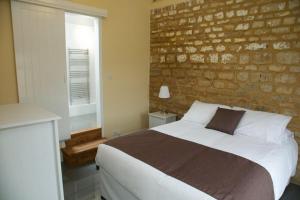 a bedroom with a large bed and a brick wall at Pheasants Roost at Tove Valley Cottages in Towcester