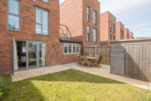 a patio with a table and chairs in front of a brick building at Stunning 3 Bedroom Home with Terrace & Parking in Trumpington