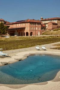 una piscina de agua con 2 sillas y un edificio en Le Corti di San Rocco, en Cossombrato