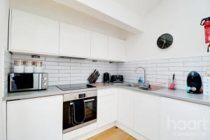 a white kitchen with white cabinets and a microwave at Lovely 1 Bedroom Flat with Free Off Road Parking in Chesterton