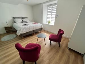 a bedroom with a bed and two chairs at LA MAISON D'ALPHONSE, charmante, centre historique 4-6pers in Quimperlé