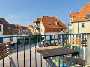 un banc en bois assis sur un balcon avec des bâtiments dans l'établissement COC - La Dune, à Wissant