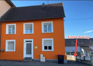 una casa naranja con una flecha roja apuntando a un techo naranja en Suite 2 lits Auberge du Manala Hôtel 24 24 proche Basel, en Saint-Louis