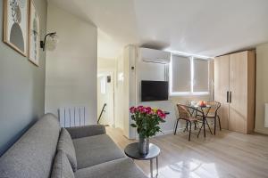 salon z kanapą i stołem z kwiatami w obiekcie Residence Center of Paris by Studio prestige w Paryżu