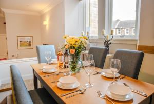 The Kinross Residence في كينروس: طاولة غرفة الطعام مع نظارة والزهور عليها