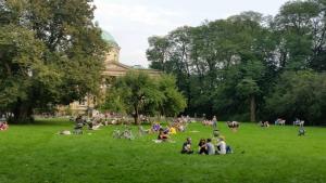 un gruppo di persone sedute sull'erba di fronte a un edificio di Warszawianka Studio a Varsavia