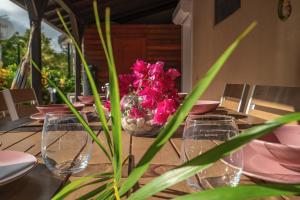 a table with glasses and a vase of pink flowers at Villa La Luz in Sainte-Anne