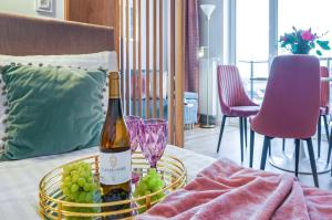 een fles wijn en een mand met druiven op een bed bij 4 Styles Apartment Rose z miejscem postojowym w garażu podziemnym in Toruń