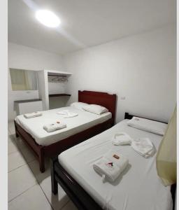 two beds in a room with white towels on them at La Posada Casa Hostal in San Vicente de Chucurí