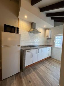 una cucina con armadietti bianchi e frigorifero di Precioso ático a Santander