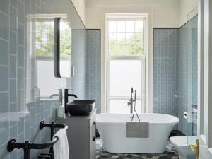 ein Badezimmer mit einer weißen Badewanne und blauen Fliesen in der Unterkunft Redrock House in Yelverton