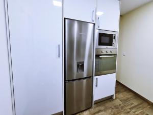 a kitchen with a stainless steel refrigerator and a microwave at MR House - Self Check-in in Coimbra