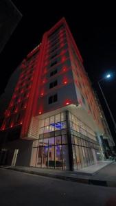 a tall building with red lights on it at night at King Hotel Karbala in Karbalāʼ