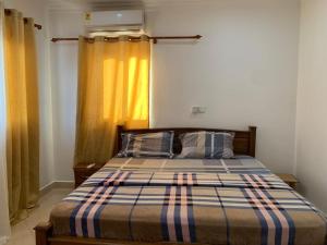 1 dormitorio con 1 cama con edredón a rayas y ventana en The Greens Estate, en Madina