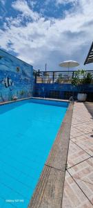 a large blue swimming pool with an umbrella at Pousada do Farol Bar e Restaurante in Vila Velha