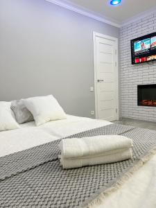 a white bedroom with a bed and a tv at Bella White Apartment in Chişinău