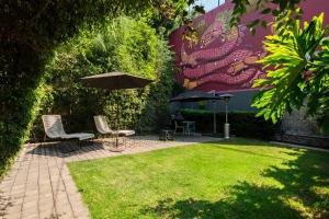 a patio with two chairs and an umbrella and grass at Pug Seal Polanco Allan Poe in Mexico City