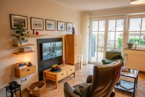 sala de estar con TV de pantalla plana y sillas en Birkenhof App 65 "Dünennest", en Wustrow