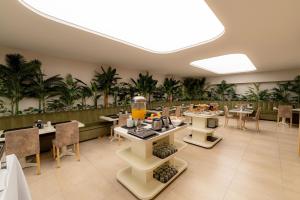 馬德普拉塔的住宿－賽納科酒店，一间设有桌椅的餐厅,种植了棕榈树
