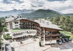 un grand bâtiment avec des voitures garées devant lui dans l'établissement Krumers Alpin – Your Mountain Oasis, à Seefeld in Tirol