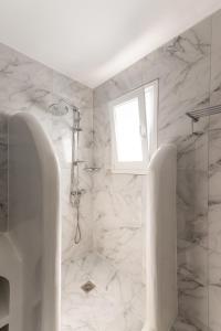 a white bathroom with a shower and a window at Anamnisi Mykonos in Mikonos +22 photos