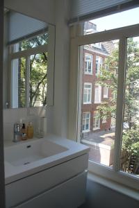 Great Apartment Amsterdam في أمستردام: حمام مع حوض أبيض ونافذة