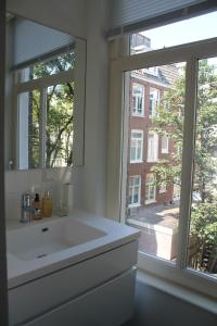 een badkamer met een witte wastafel en een raam bij Great Apartment Amsterdam in Amsterdam