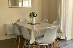a table with white chairs and a vase with flowers on it at Beach Braunton Spacious 3 Bed House By Dreamy Homes Short Lets & Serviced Accommodation Free Parking in Braunton