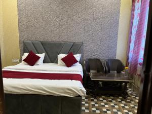 a bedroom with a bed with red pillows and a table at Priyakant inn in Vrindāvan