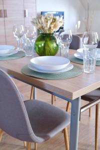 uma mesa de madeira com um vaso verde com pratos e copos em Trón Apartman em Siklós