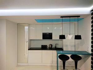 a kitchen with white cabinets and a table with stools at Exclusive Kielce in Kielce