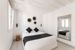 a white bedroom with a bed and a mirror at Anamnisi Mykonos in Mikonos