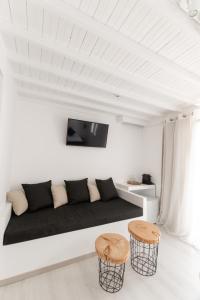 a living room with a black couch and two stools at Anamnisi Mykonos in Mýkonos City
