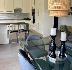 Una cocina y un comedor con una mesa de cristal y sillas. en LAUSANNE PULLY sunny apartment on lakeside street and direct bus to Lausanne train station, en Pully