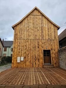 um grande celeiro de madeira com um deque de madeira em Le Grain Noble - Demeure Alsacienne de Caractère em Zellwiller
