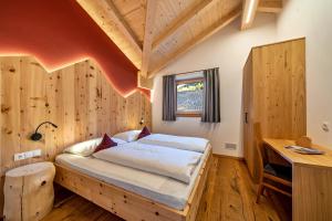 1 dormitorio con 1 cama en una habitación con paredes de madera en Ferienwohnung Gruberhof en Verano