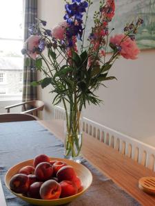 een fruitschaal op een tafel met een vaas met bloemen bij Stunning apartment in the centre of Corbridge in Corbridge