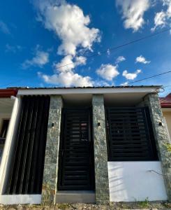 ein Haus mit schwarzen Rollläden und blauem Himmel in der Unterkunft KENNA'S NOOK in Butuan