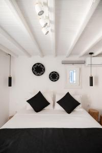een slaapkamer met een wit bed met zwarte kussens bij Anamnisi Mykonos in Mykonos-stad