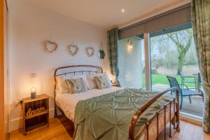 a bedroom with a bed and a large window at Firecrest in Somerford Keynes