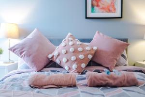 Una cama con almohadas rosas encima. en OPP Liverpool - Perfect for contractors and travellers, BIG SAVINGS booking 4 nights or more! en Liverpool