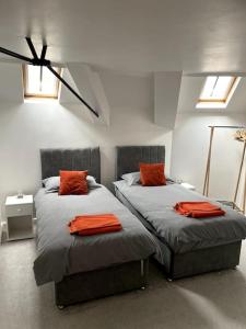a bedroom with two beds with orange pillows on them at Stylish apartment in the centre of Hebden Bridge. in Hebden Bridge