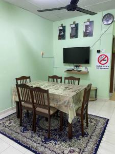comedor con mesa, sillas y TV en Aziz homestay, en Gemencheh
