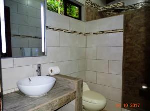 ein Badezimmer mit einem weißen Waschbecken und einem WC in der Unterkunft Casa Caribbean Coconut in Cahuita