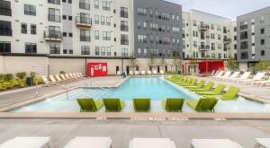 una piscina vacía con sillas verdes y edificios en CozySuites Lavish SDO Lawrenceville en Pittsburgh