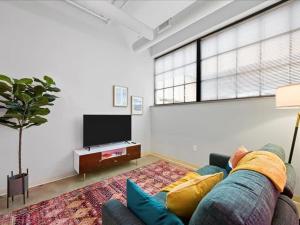 uma sala de estar com um sofá e uma televisão de ecrã plano em CozySuites Roomy 1BR, Downtown Pittsburgh em Pittsburgh