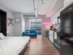 a bedroom with a bed and a kitchen with a blue chair at CozySuites Trendy SDO, Lawrenceville in Pittsburgh